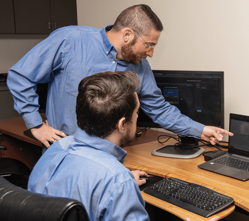 two GANT IT employees working on computer with one pointing to laptop screen