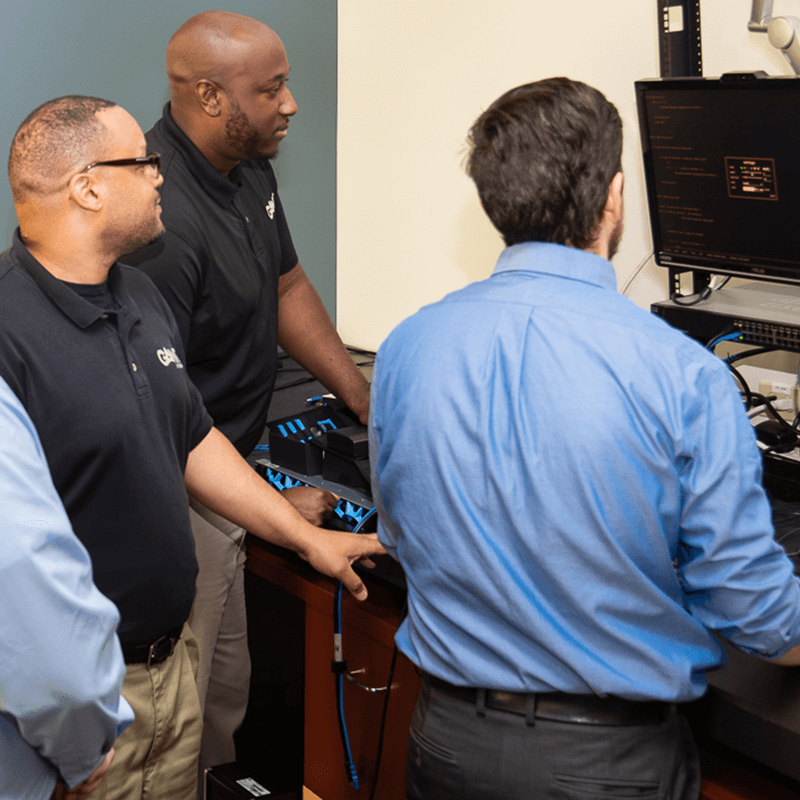 group of IT employees gathered around computer and parts